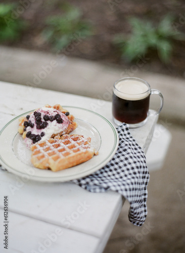 a belgian waffle breakfast with coffee on picnic table outside