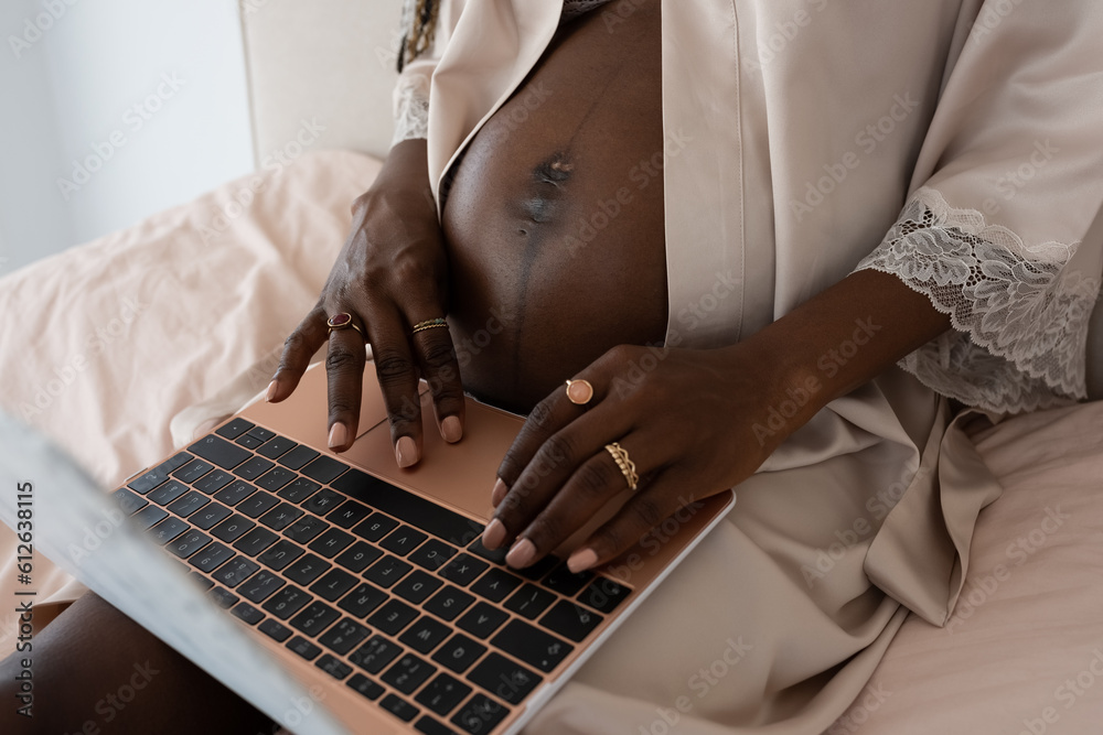 © Milles Studio/Stocksy - Black pregnant woman browsing computer