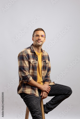 The casually clothed man sitting on a bar stool