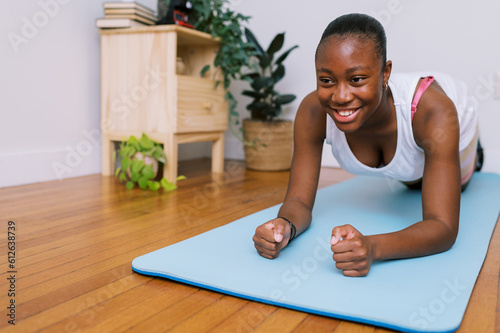 smiling black teen doing plank on yoga mat