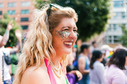 Curly blond Woman with glitter on her face at Pride laughing photo