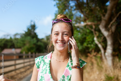 Joyful woman calling by phone in nature at daytime