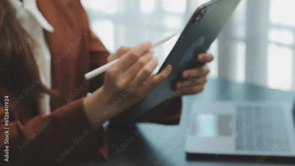 Portrait of Young Asian woman hand freelancer is working her job on computer tablet in modern office. Doing accounting analysis report real estate investment data, Financial and tax systems concept. Portrait of Young Asian woman hand freelancer is working her job on computer tablet in modern office. Doing accounting analysis report real estate investment data, Financial and tax systems concept.