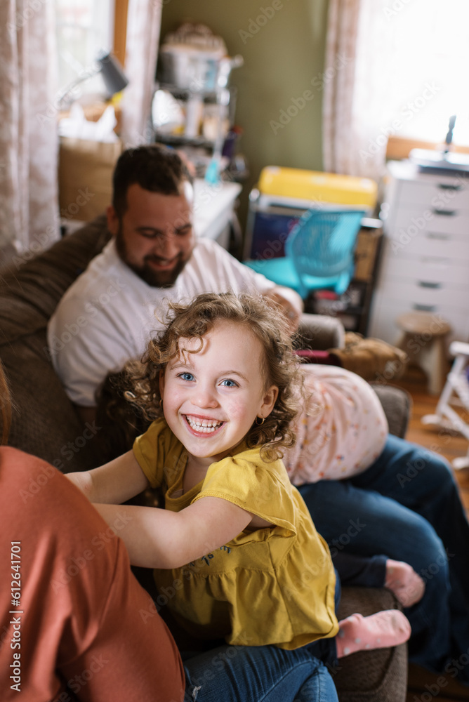 Happy toddler girl smiling big while playing with her family indoors Happy toddler girl smiling big while playing with her family indoors
