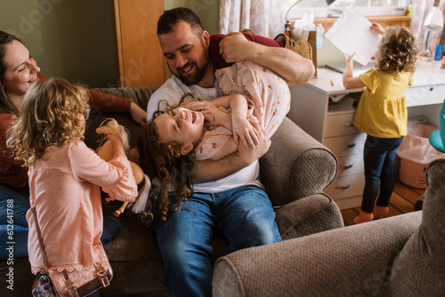Smiling happy family playing with kids on couch in home