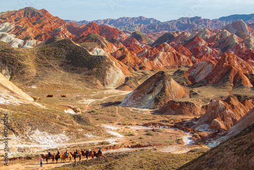 Travellers with camels in Colorful mountain in Danxia landform in Zhangye, Gansu of China. Silk road landscape
