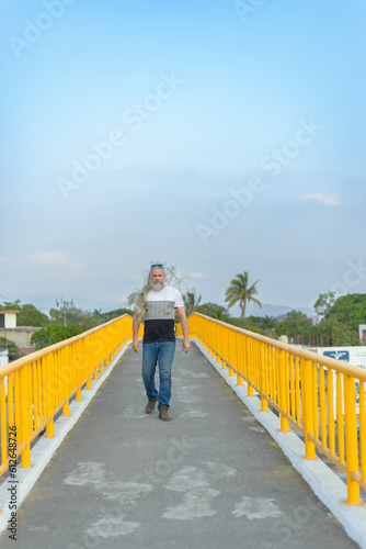 Long-haired gray-haired man on a pedestrian bridge.