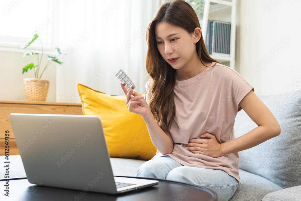 Telehealth, Telemedicine concept. Flatulence asian patient young woman stomach ache suffer from food, discussing with doctor video call with computer at home, during online consultation in living room Telehealth, Telemedicine concept. Flatulence asian patient young woman stomach ache suffer from food, discussing with doctor video call with computer at home, during online consultation in living room