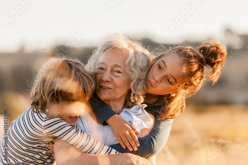 Grandmother and grandchildren hug each other happily by the field