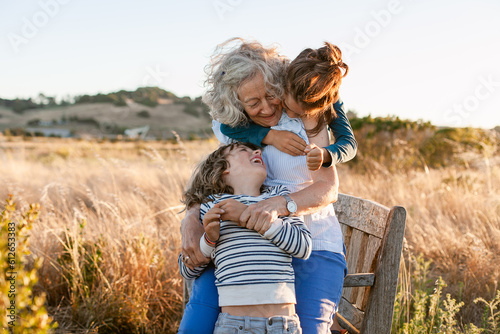 Grandmother and grandchildren embraced in golden california