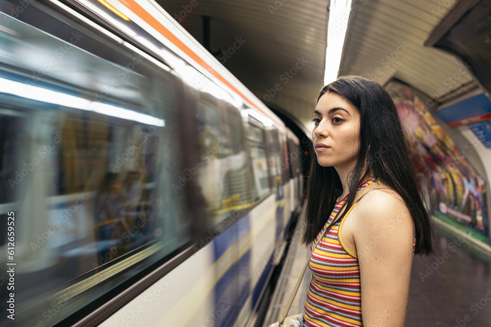 Young woman waiting for the train standing on the subway platform Young woman waiting for the train standing on the subway platform