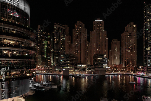 Night view from the promenade of Dubai Marina with illuminated skyscrapers  a water channel  yachts and ships in Dubai city  United Arab Emirates