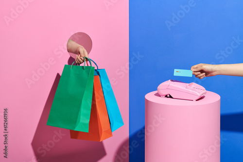 female hand pays with wireless bank terminal and holding shopping bags