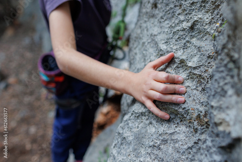 rock climber's hand close-up. child rock climber in a blue protective helmet overcomes the route in the mountains. children's sports in nature.