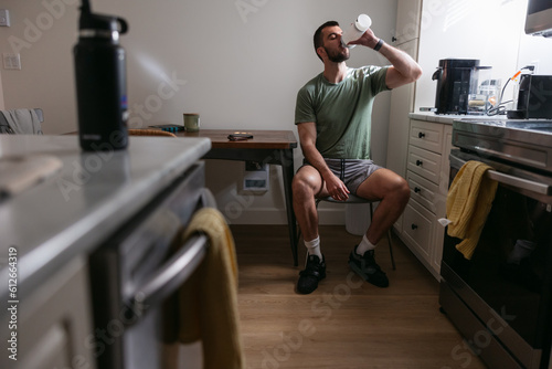 Man drinking from shaker cup in the kitchen before workout.