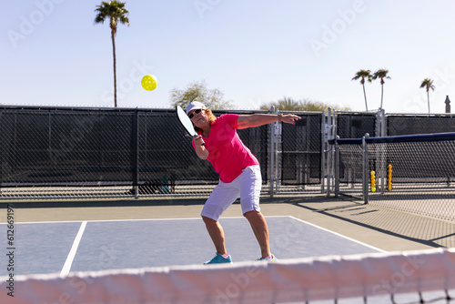 Senior Citizen Pickleball player looks to swing accurate  at ball  photo