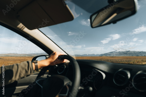 Unrecognizable Man driving car in mountain, hands on wheel. 