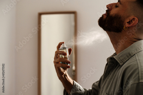 Man spraying perfume to his neck photo