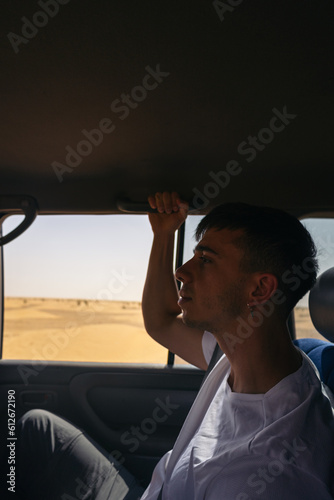 Wallpaper Mural Young man traveling by car through sand dunes in the desert Torontodigital.ca