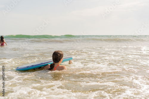 Girl with begginer surfboard by the shoreline photo