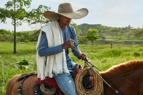 Young cowboy portrayed riding on his horse on a Colombian farm photo