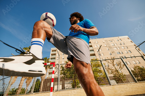 Energetic black football player kicking ball