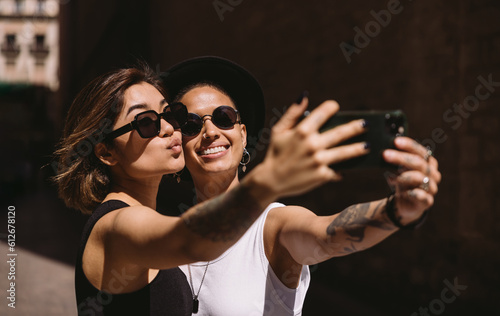 Cheerful young girlfriends taking selfie on street photo