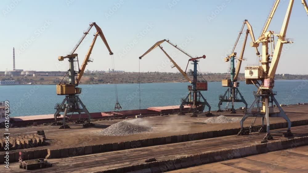 Sea port cranes upload something from a pile in the tanker. Logistic and transportration concept. Sea port cranes upload something from a pile in the tanker. Logistic and transportration concept.