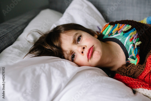 boy lays on couch at home while sick with cold and flu