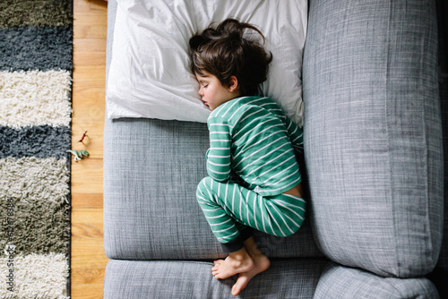 Ovehrhead view of boy on couch at home while sick with cold and flu