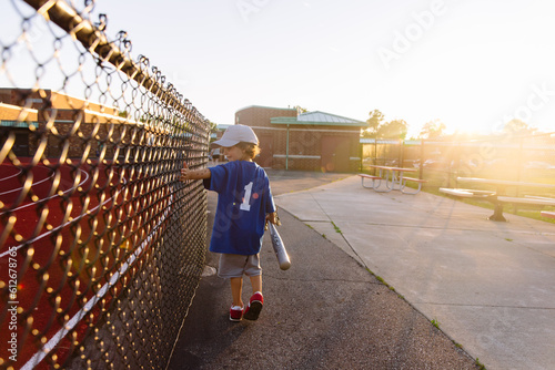 little boy walks down path after a bace-ball game. photo