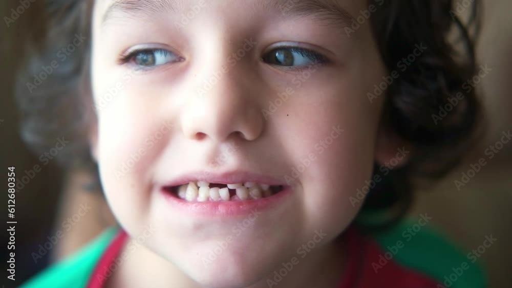 A little curly-haired boy shows a loose milk tooth. A little curly-haired boy shows a loose milk tooth.
