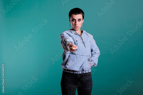 Displeased angry woman pointing index finger in front of camera screming during studio shot on isolated background. Upset nervous female having mental breakdown, disappointment expression