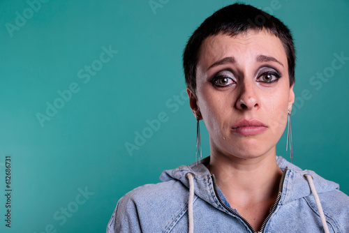 Portrait of depressed unhappy caucasian female looking at camera while crying in studio with isolated background, person having mental breakdown. Worried woman with grief expression