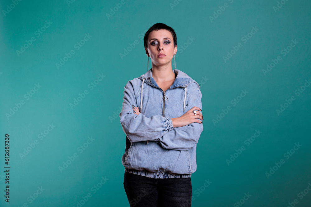 Attractive brunette woman with short hair standing with arms crossed looking at camera while posing in studio with isolated background. Fashionable model having confident expression Attractive brunette woman with short hair standing with arms crossed looking at camera while posing in studio with isolated background. Fashionable model having confident expression
