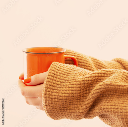 female hands with orange cup of coffee on white background