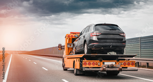 Tow truck with a broken car on a road. Tow truck transporting car on the highway. Car service transportation concept. Roadside Rescue.