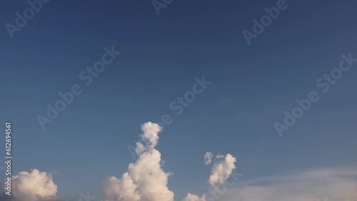 Movement of white clouds on a blue sky background, which is turning dark.Time lapse