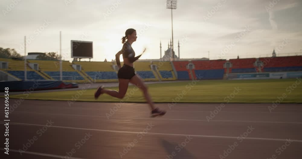 Fit female sprinter running fast in stadium during morning training