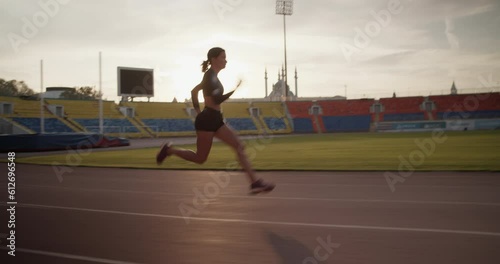 Fit female sprinter running fast in stadium during morning training