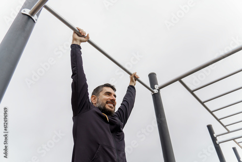 young man training on a pull-up bar in an outdoor gymnasium photo