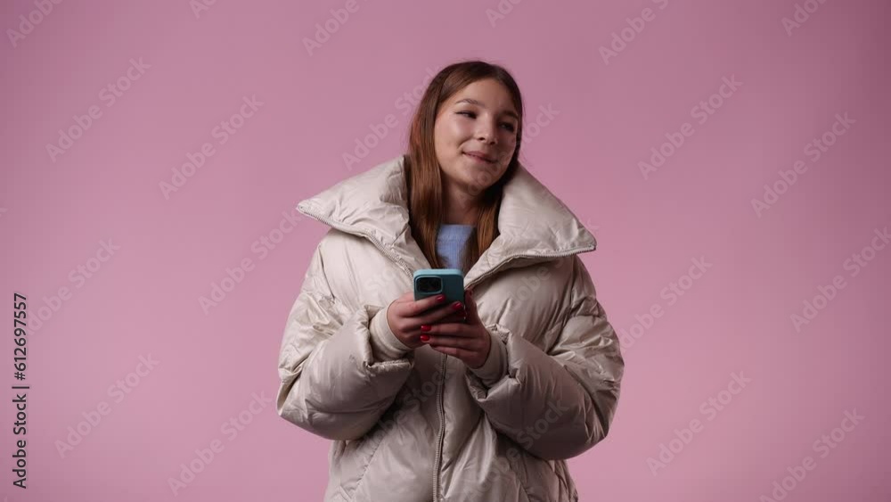 4k video of one girl using her phone over pink background. 4k video of one girl using her phone over pink background.
