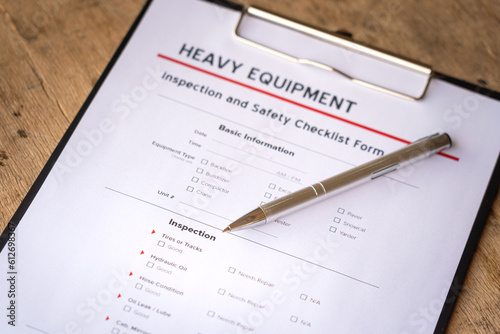 A ballpoint pen is placed on heavy equipment inspection and checklist form. Industrial safety working practive scene and object photo, close-up and selective focus at pen's part.
