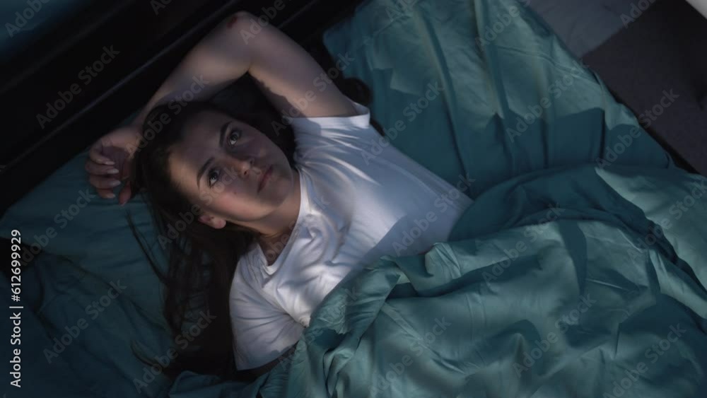 Sleep disorder, insomnia concept. Young woman lying on the bed awake at night