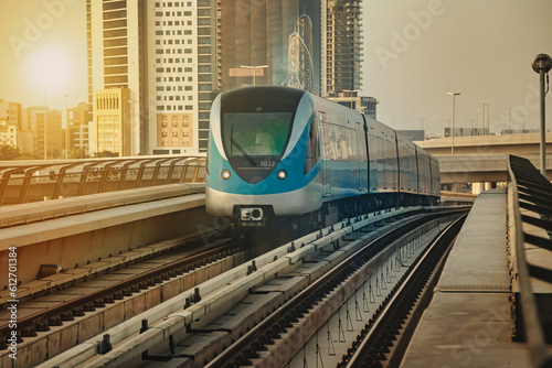 View of train on railroad of Dubai modern subway in downtown at urban skyscrapers background. Backdrop of city metropolitan metro in desert arabic country. Public transport concept. Copy ad text space