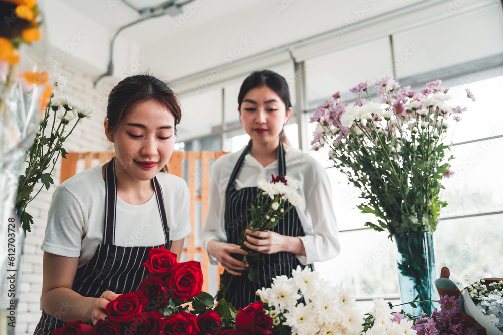 Two female employees are arranging flowers in a flower shop smiling and happy face.