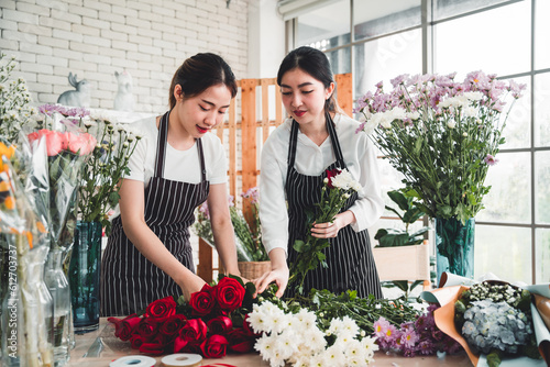Two female employees are arranging flowers in a flower shop smiling and happy face.