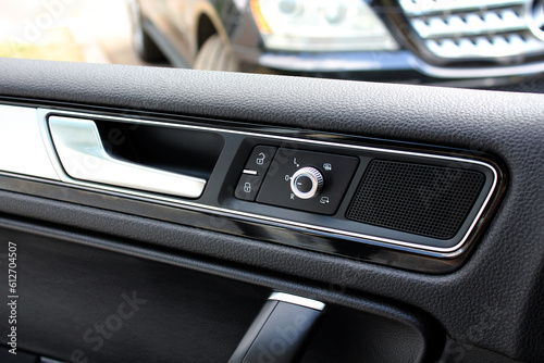 Interior of a modern car. Inner driver door handle with lock unlock buttons. Modern Car Door Panel. Speaker in the car door.