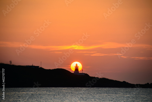 At dusk, the sun is behind the lighthouse. The Fugui Cape Lighthouse in Shimen. Taiwan photo