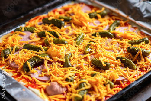 Raw pizza with pickles and cheese. Cooking homemade pizza.